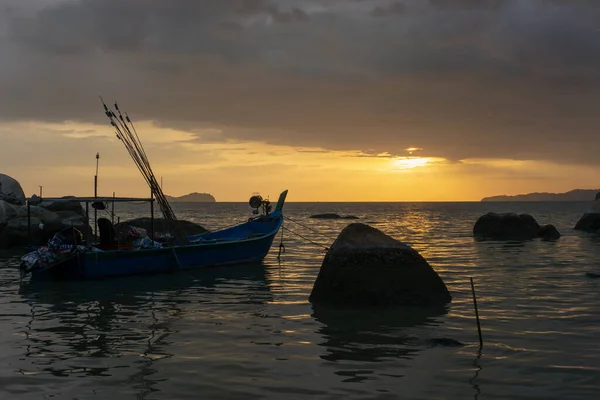 Un parco di barche da pesca accanto a una grande roccia vicino alla costa durante il tramonto . — Foto Stock