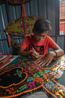 Tanımlanamayan bir adam geleneksel Malay ay uçurtması şeklini kesmiş..