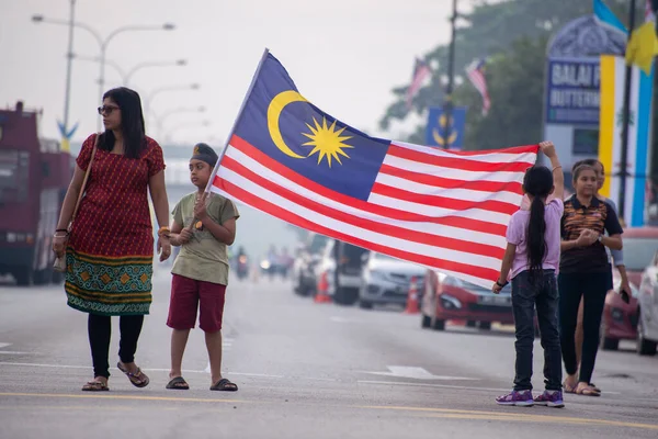 En malaysisk familj håller flaggan på gatan under firandet av Merdeka. — Stockfoto