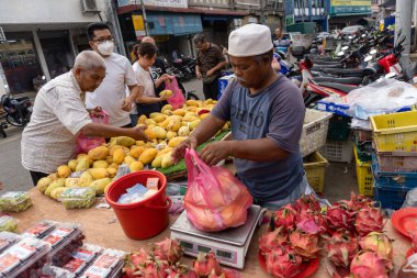 Tüccar, Malezya sabah pazarında meyve satıyor.