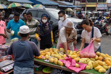 İnsanlar Malezya sabah pazarından meyve alıyorlar.