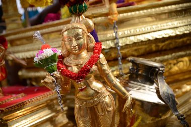 A gold statue of gold chariot with the colorful flower hand on the neck
