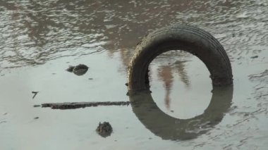 Kirli çamurda eski araba lastiği.