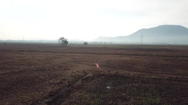 Rotational follow shot of Malaysia flag at vast open wet land. — Stock Video