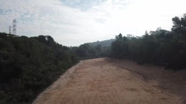 Ağaçların açık olması nedeniyle sarı toprak yolu