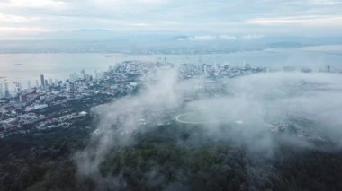 Arka planı Penang Bölgesi ve George Kasabası olan sisli bulutların üzerinde uçan bir hava aracı..