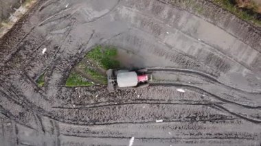 Havadan bakıldığında traktör küremesi çeltik tarlasında toprağı işliyor..
