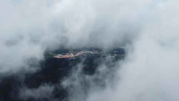 Leć nad mglistym niebem z zieloną dżunglą i małym miasteczkiem Balik Pulau w tle. — Wideo stockowe