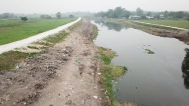 Nehir kıyısının etrafındaki çöplerle karanlık, kirlenmiş nehre doğru uçuyorlar.