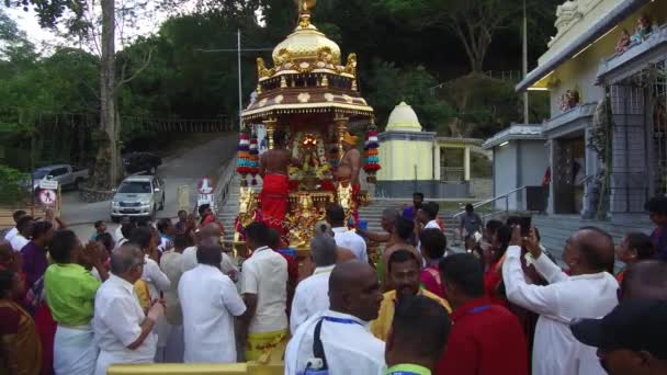 Priest hold brass candelabra with lit oil lamps in front of gold chariot. — Stock Video