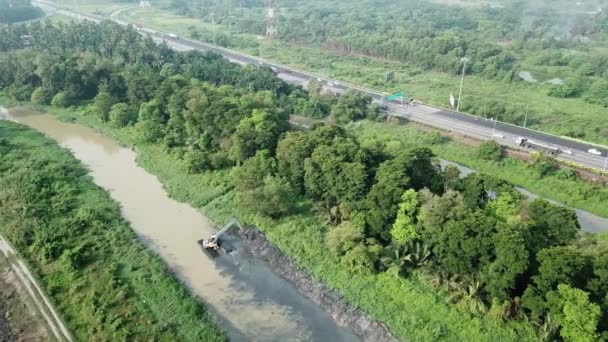 Luchtfoto graafmachine graven in rivier met achtergrond drukke snelweg. — Stockvideo