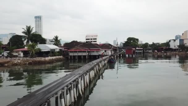Een man vissen met net bij houten brug clan steiger met KOMTAR gebouw — Stockvideo