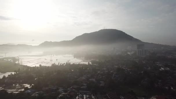 Vuelo aéreo sobre el pueblo malayo en la mañana brumosa con una colina al fondo . — Vídeos de Stock