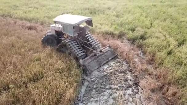Aerial follow back of tractor plowing the rice field. — Stock Video