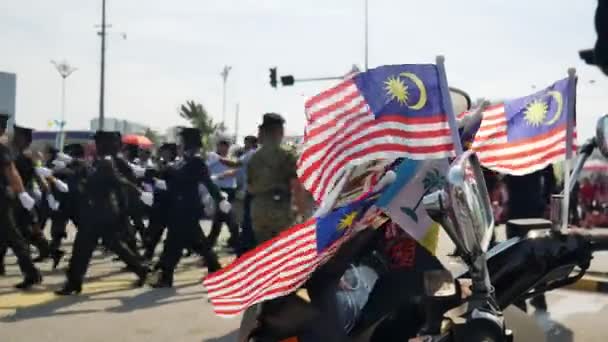 Malaysia flag waving with background bokeh parade of policemen. — Stock Video