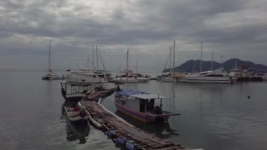 Balıkçı tekneleri arka plandaki ahşap köprü ve yatın yanına park eder..