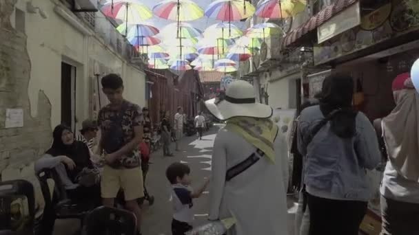 La gente disfruta del callejón con paraguas de colores cuelgan . — Vídeo de stock