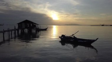 Siluet balıkçısı, tekneyi denizde ahşap kulübenin yanına çek..