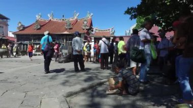 Dilenci, Merhamet Tanrıçası Tapınağı 'nın önünde yerde yemek yiyor..