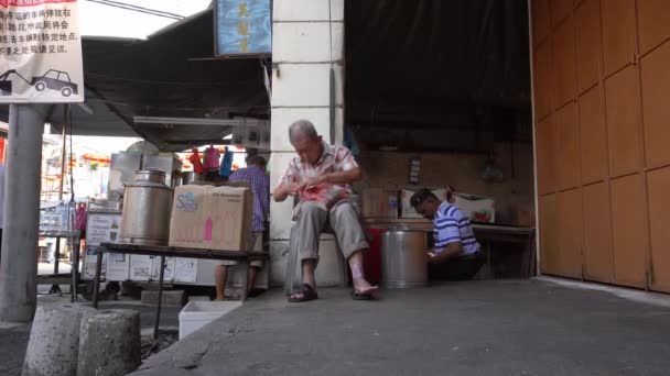 Een oude man zit op straat. — Stockvideo