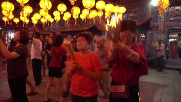 Люди молятся божествам в храме, украшенном красным фонарем . — стоковое видео