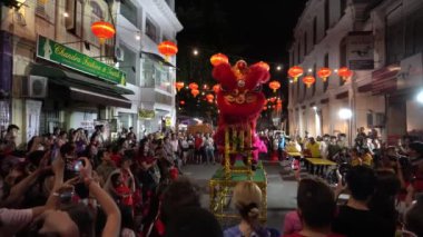 Kırmızı aslan sahneye zıplıyor. Kalabalık kamera ve cep telefonuyla fotoğraf çekiyor.