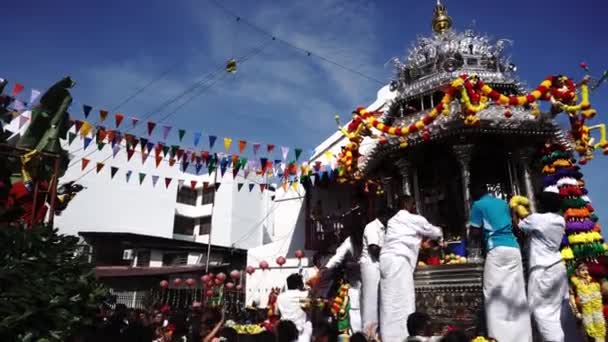 Tilt shot Hindu devotees offering in front of silver chariot under blue sky. — Stock Video