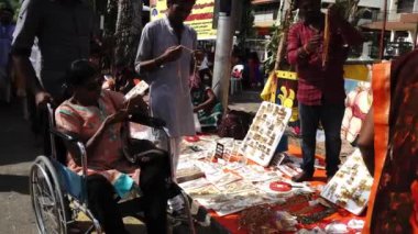Thaipusam 'daki tezgahta eski bir tekerlekli sandalyede alışveriş yapan bir fanatik.