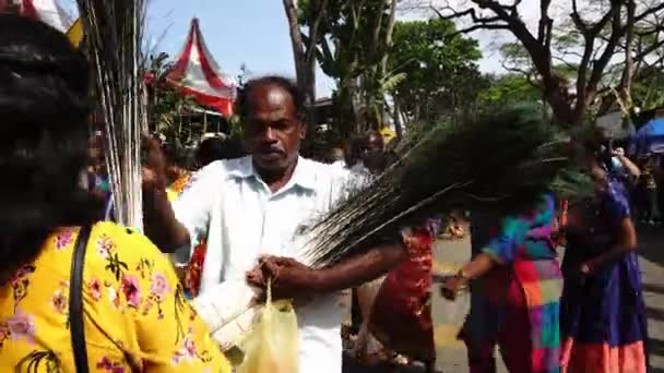 Μια ηλικιωμένη γυναίκα αγοράζει φτερά παγωνιού κατά τη διάρκεια Thaipusam. — Αρχείο Βίντεο