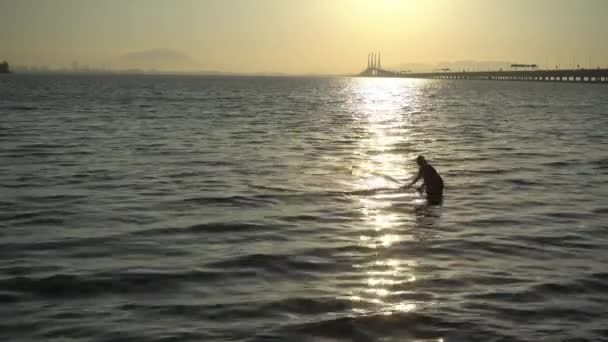 Fisherman cast net near the Penang Bridge in sunrise morning. — Stock Video