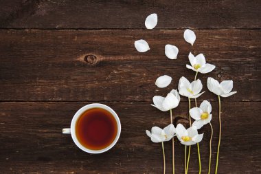 Bir fincan çay, beyaz çiçekli, anemon ahşap arka plan üzerinde