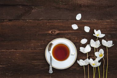 Bir fincan çay, beyaz çiçekli, anemon ahşap arka plan üzerinde