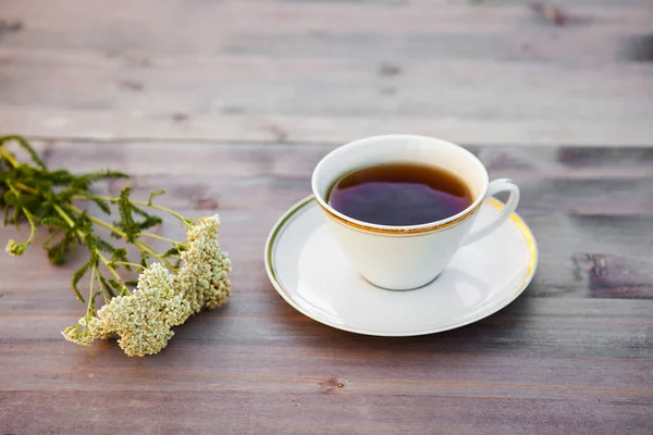Tazza di tè su un tavolo di legno, con fiori bianchi — Foto Stock