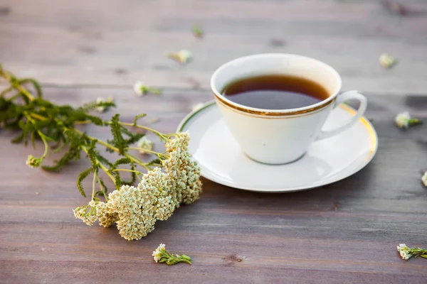 Tazza di tè su un tavolo di legno, con fiori bianchi — Foto Stock