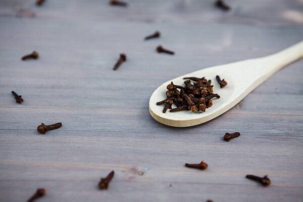 Seasoning cloves on a wooden spoon, background