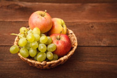 Taze meyveler, elma ve üzüm sepeti ahşap arka plan üzerinde. 