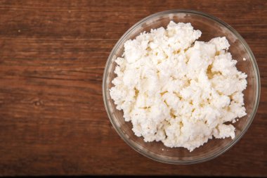 Ahşap arka plan üzerinde bir tabak içinde taze peynir. Uygun n