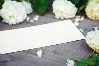 Kağıt ahşap bir masada, beyaz çiçekler