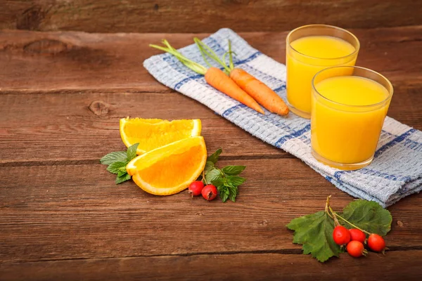 Refreshing orange-carrot juice in a glass on a wooden background