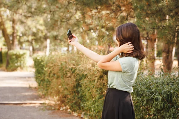Genç bir kız dışarıda selfie çekiyor..