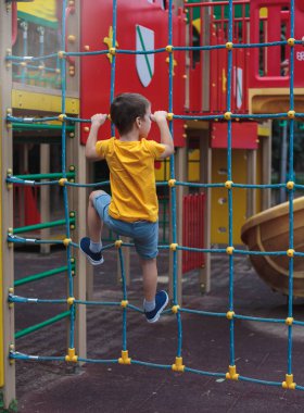 Parktaki çocuk ağa tırmanıyor, dikiz aynasından. Çocuk sporları, eğlence, hobiler. Sağlıklı çocuk.