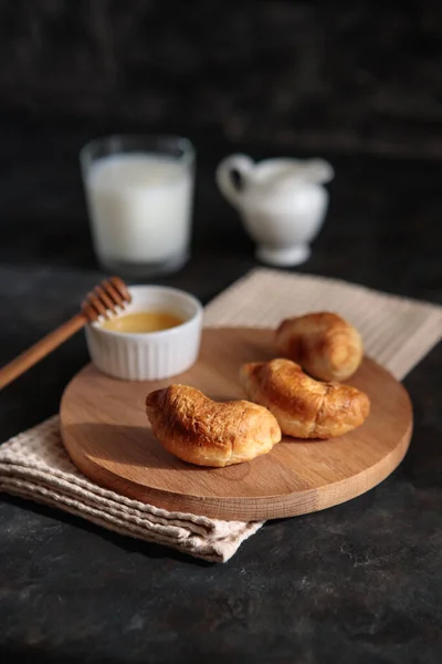 Ballı ve sütlü kruvasanlar, yakın plan, koyu arka plan. Fransız kahvaltısı. Mesaj için yer var. Tatlı.