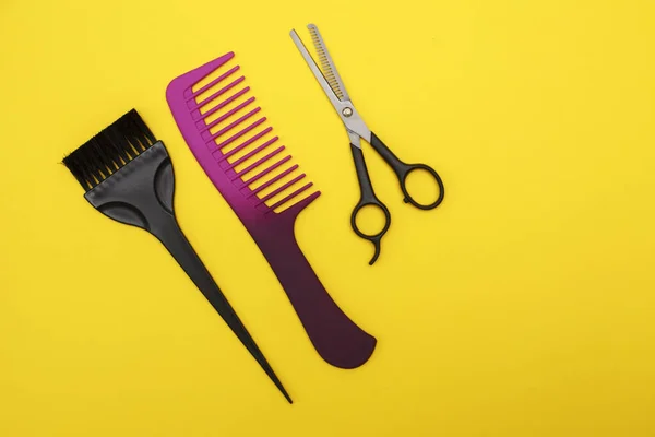 thinning scissors, comb and hair brush on a yellow background, space for text. Barber Tools. flat lay