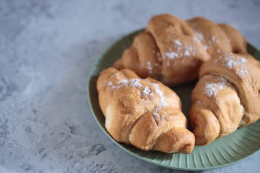 Yeşil tabakta kruvasanlar, yaklaşın. Metin için boşluk, taze hamur işleri.