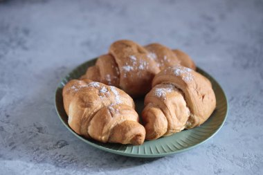 Yeşil tabakta kruvasanlar, yaklaşın. Metin için boşluk, taze hamur işleri.