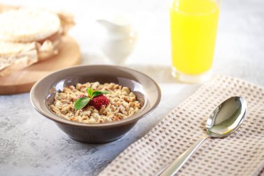 Bir tabakta süt ve ahududu, tam tahıllı ekmek ve taze sıkılmış meyve suyu ile pişirilmiş granola. Sağlıklı kahvaltı. Nefis müsli..