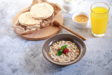 Sağlıklı ve besleyici bir kahvaltı. Bir tabakta süt ve ahududu, tam tahıllı ekmek ve taze sıkılmış meyve suyu ile pişirilmiş granola. Nefis müsli..