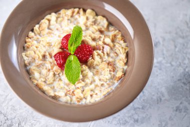 Sağlıklı kahvaltı. Sütlü tahıl gevreği ve nane aromalı ahududu. Lezzetli müsli, yakın plan.