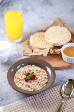 Sağlıklı ve besleyici bir kahvaltı. Bir tabakta süt ve ahududu, tam tahıllı ekmek ve taze sıkılmış meyve suyu ile pişirilmiş granola. Nefis müsli..