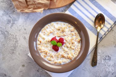 Bir tabakta süt ve ahududu ile pişirilmiş granola, yakın plan. Sağlıklı ve diyet kahvaltı. Nefis müsli..